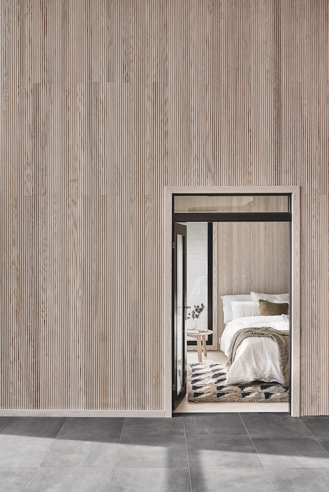 Dormitorio con sabanas de algodon y pared con listones de madera