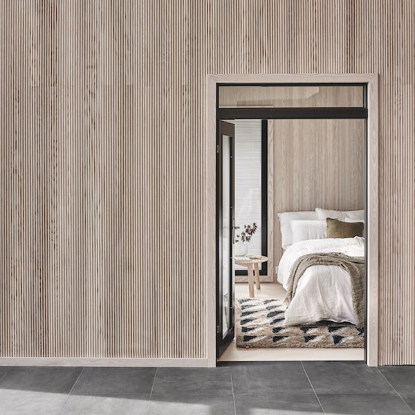 Dormitorio con sabanas de algodon y pared con listones de madera