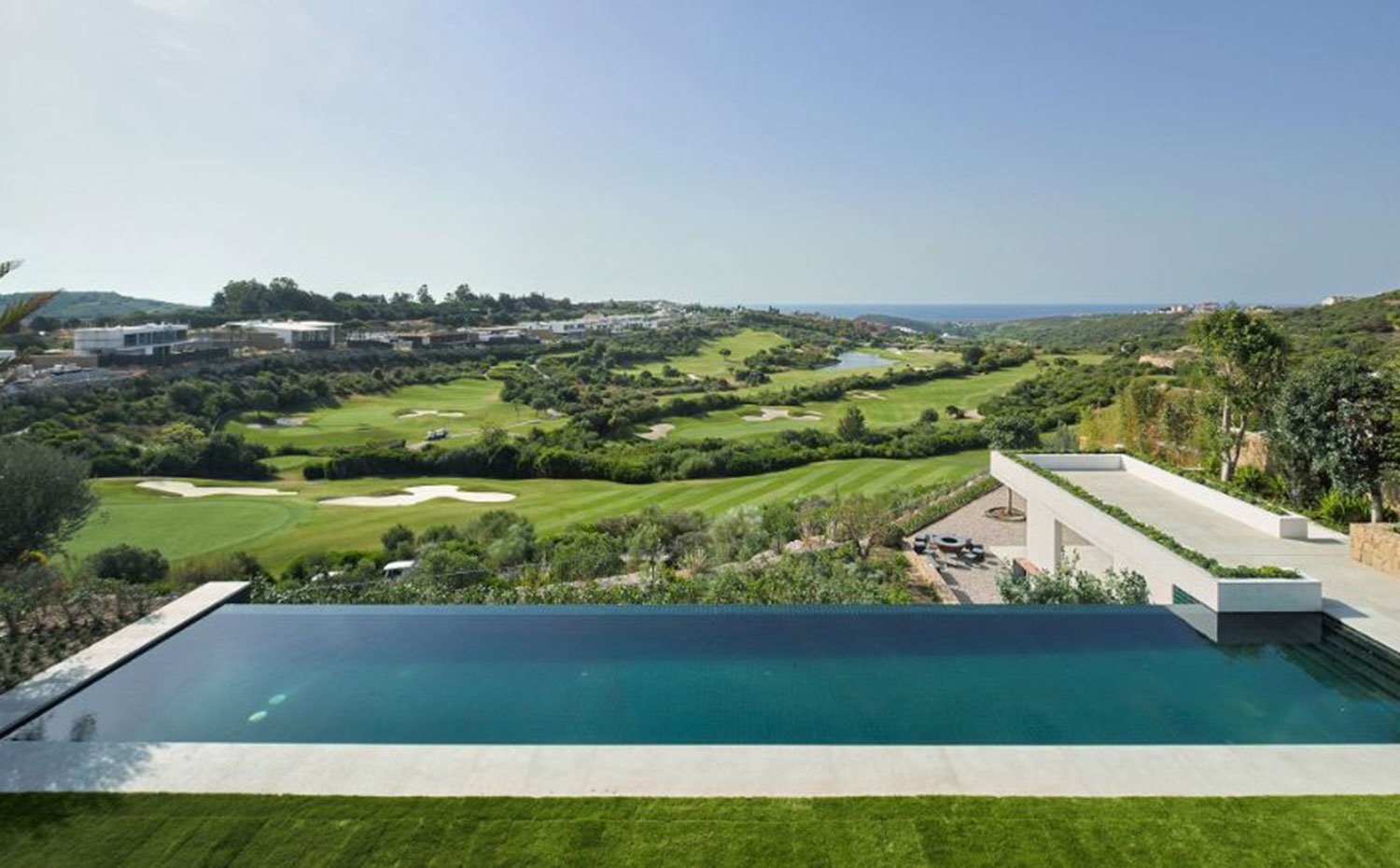 Piscina infinita en voladizo hacia paisaje de campos de golf