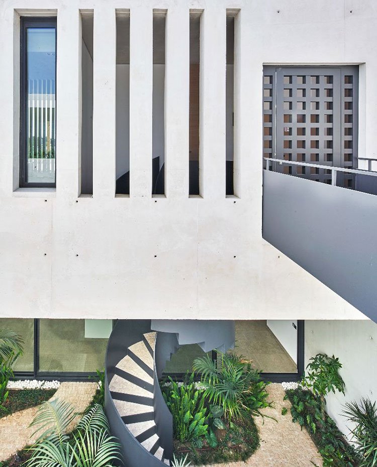 Puerta de acceso con pasarela de hierro y vista a nivel inferior con escaleras de caracol hacia patio