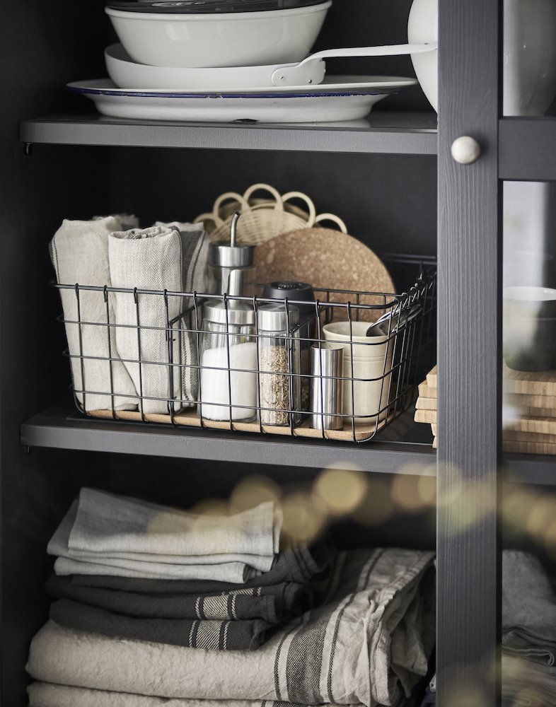 Detalle de un armario de cocina ordenado con cestas y paños de Ikea