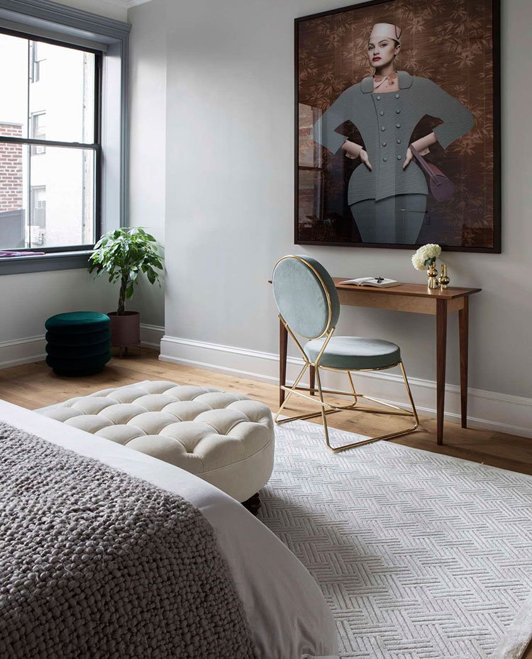 Dormitorio-con-pouf-ocre-sobre-alfombra-gris-claro,-consola-y-silla-a-pared