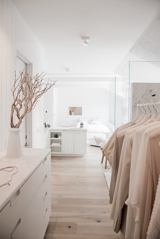 Vestidor con mueble bajo en blanco junto a zona de baño y dormitorio