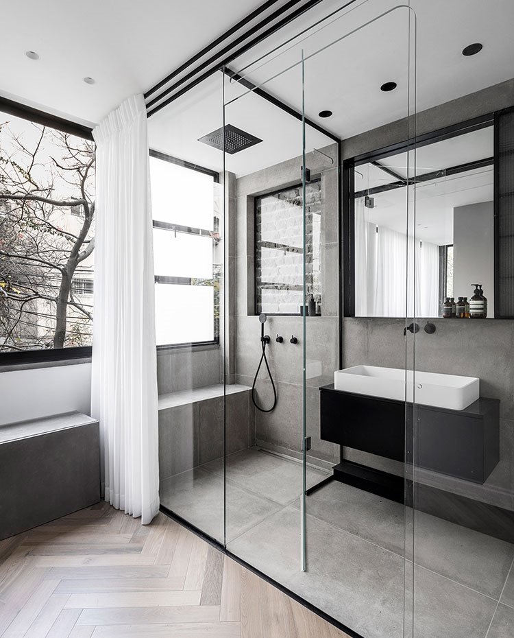 Cuarto de baño con cerramiento de cristal transparante con ducha integrada y zona de lavamanos con módulo suspendido en negro