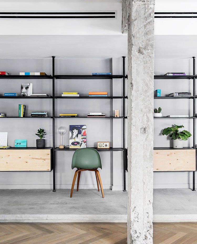 Estantería junto a salón, silla de madera y asiento verder, vigas pintadas en blanco