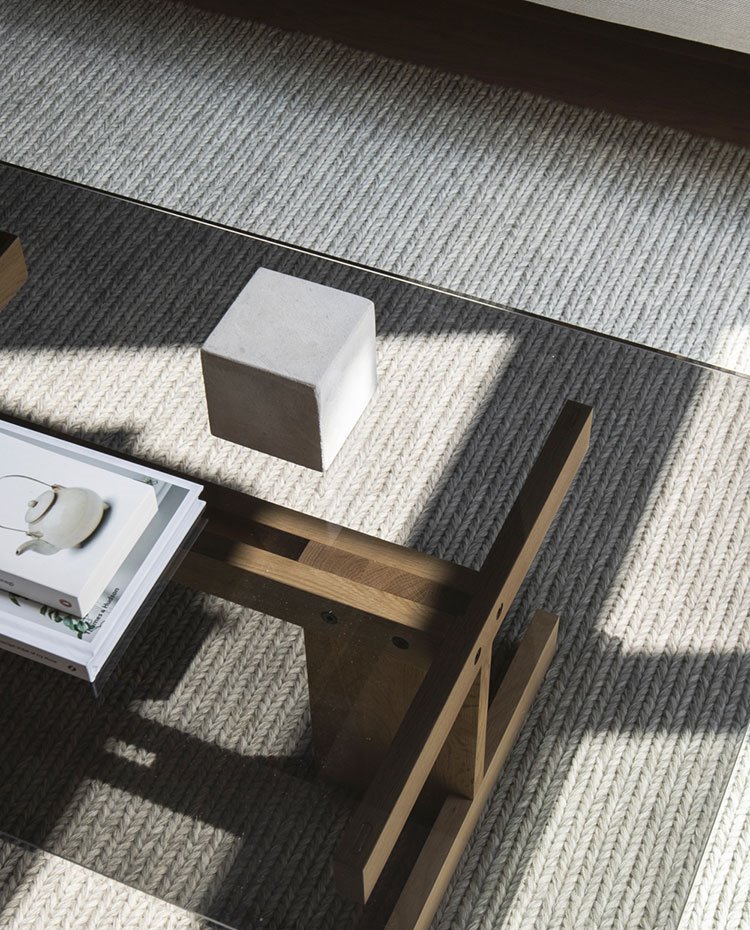 Detalle mesa de centro salón con sobre de cristal y base de madera