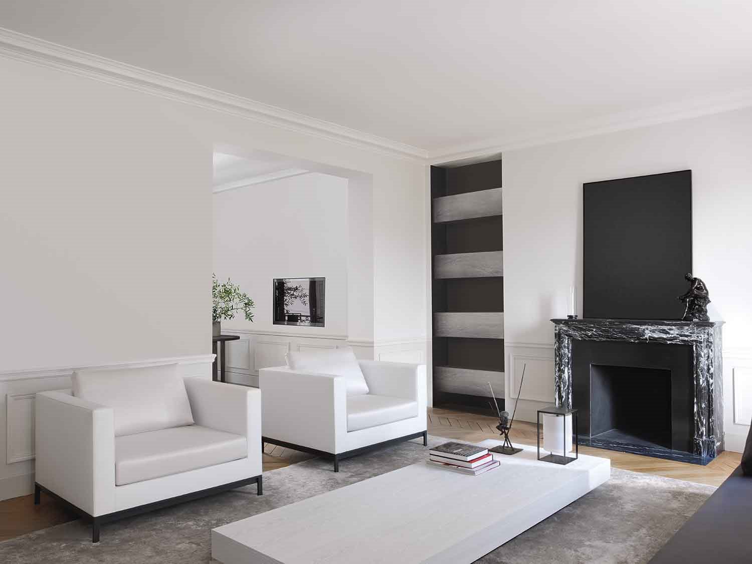 salon-con-butacas-blancas-y-chimenea-de-marmol-negro-en-piso-parisino-con-reforma-de-Guillaume-Alan