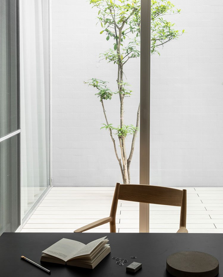 Sobre de madera en negro, silla de madera ante patio interior con tarima de madera