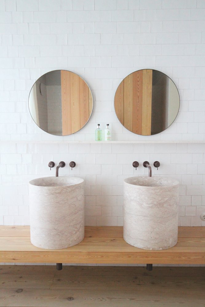 Lavabo con lavamanos de piedra y espejos redondos hotel santa clara Lisboa Aires Mateus