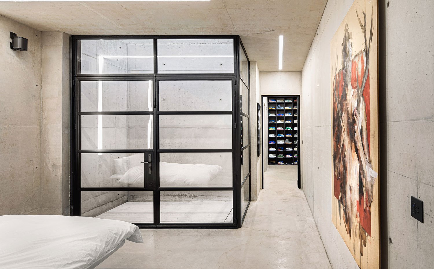 Dormitorio con revestimiento de hormigón, con patio interior y zona de vestidor con organizador de zapatillas