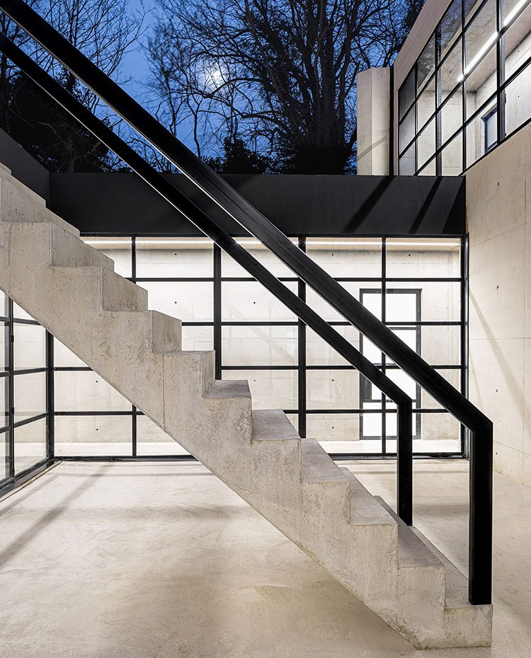 Escaleras exteriores de hormigón y acero pintado en negro, perfilería con marcos en negro y cristal transparente