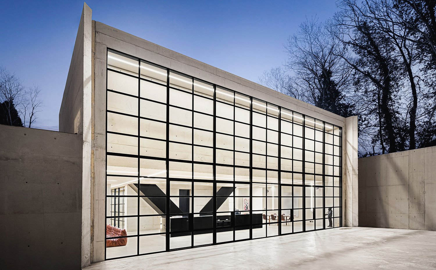 Fachada exterior con caja de hormigón y cerramiento de cristal con vista interior de zona común