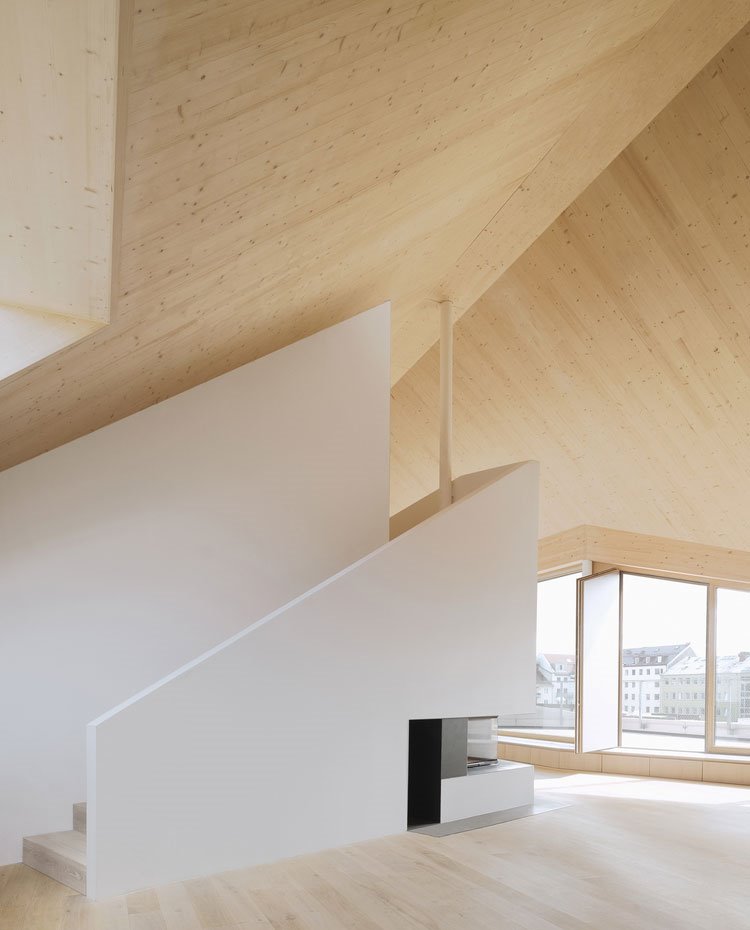 Cubierta de madera con aperturas irregulares y chimenea bajo escaleras