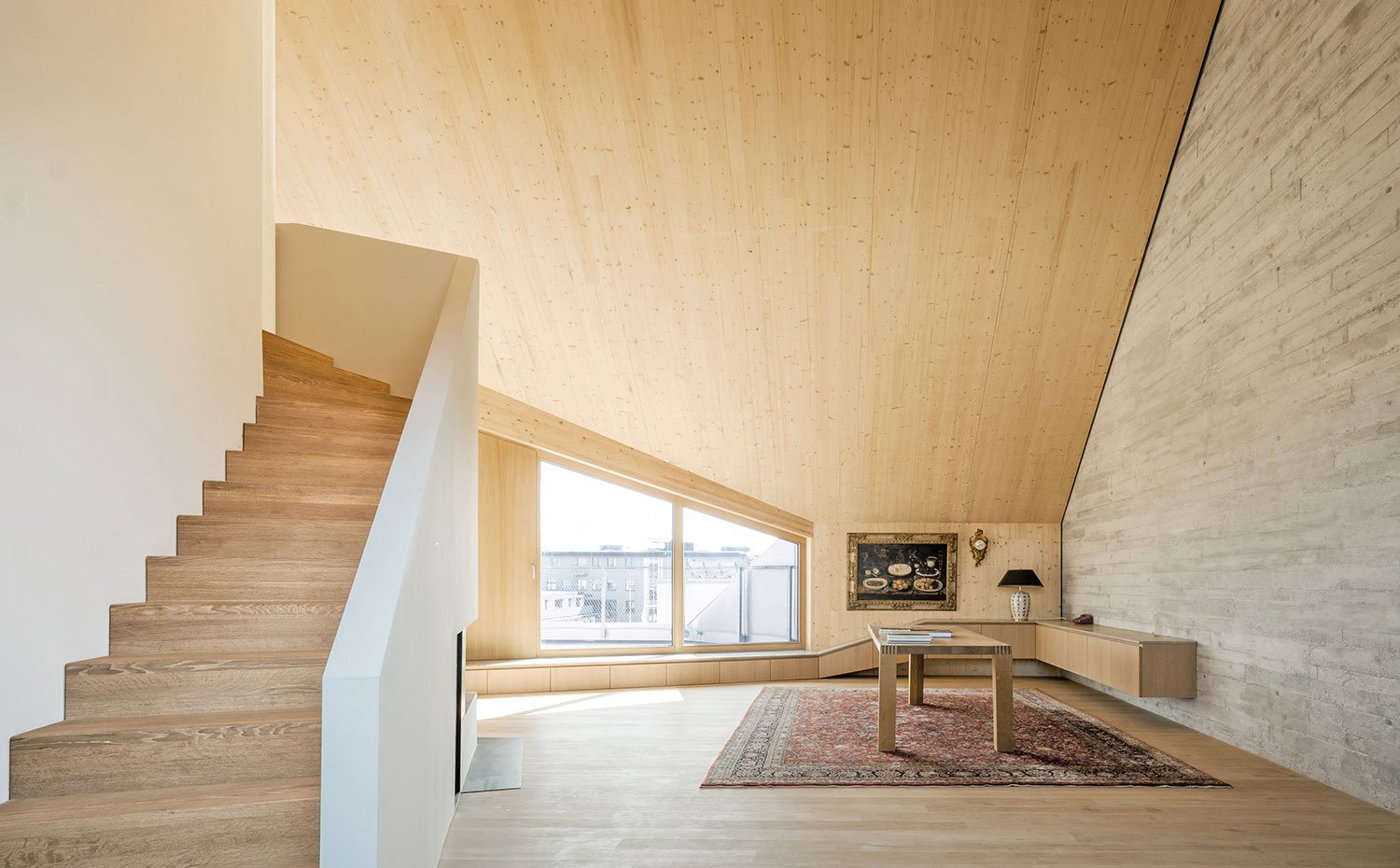 Escaleras a nivel superior, mesa de madera con módulos a juego en pared y perfil de fachada
