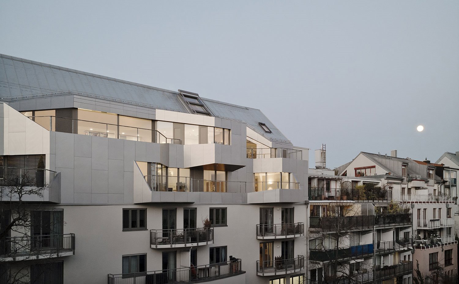 Vista exterior fachada vivienda al anochecer, con luna al fondo