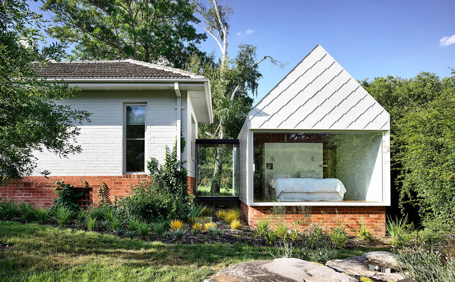 Exterior-vivienda-con-estructura-de-ladrillo-junto-a-extensión-con-dormitorio-a-la-vista