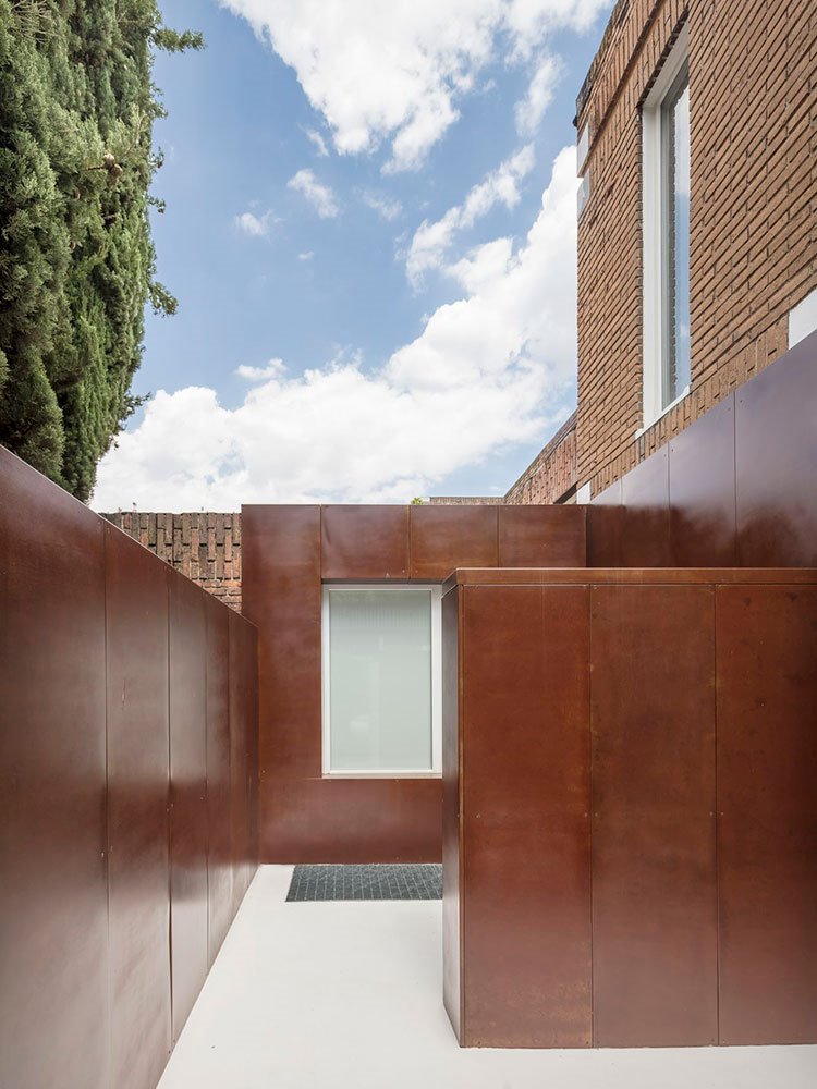 Exterior e la casa con muros revestidos de acero y ventanas