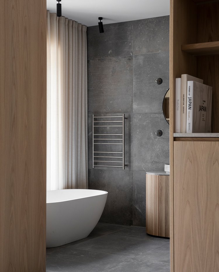 Cuarto de baño abierto junto a dormitorio con bañera exenta y mobiliario en madera clara
