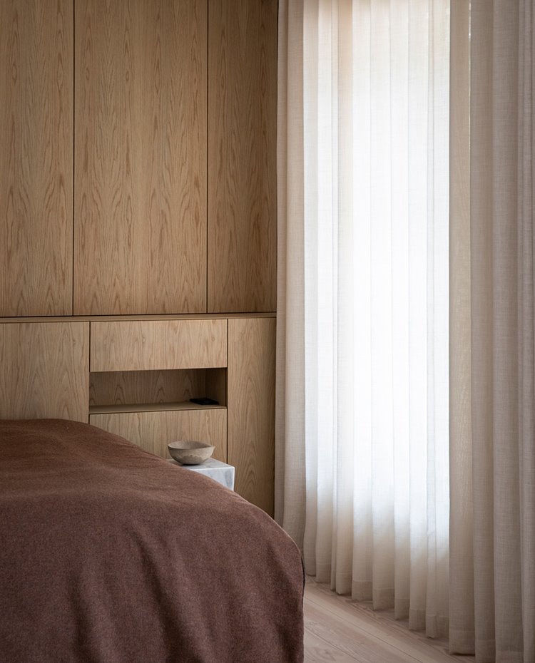 Dormitorio con mobiliario de madera personalizado y cortinas blancas y crudas para las aperturas