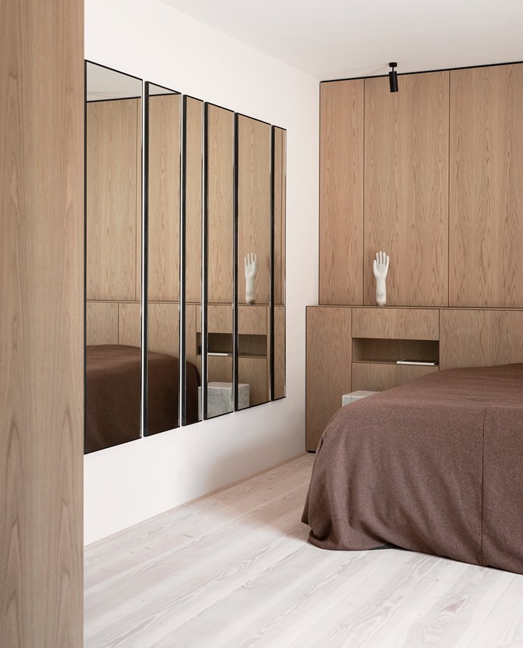 Dormitorio con mobiliario y cabecero hecho a medida en madera, serie de espejos en frente de pared