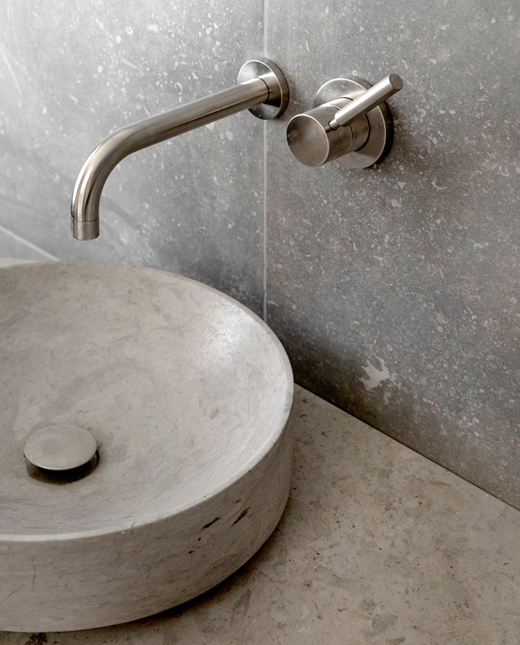 Lavamanos de piedra en gris sobre encimera de zona de lavabo