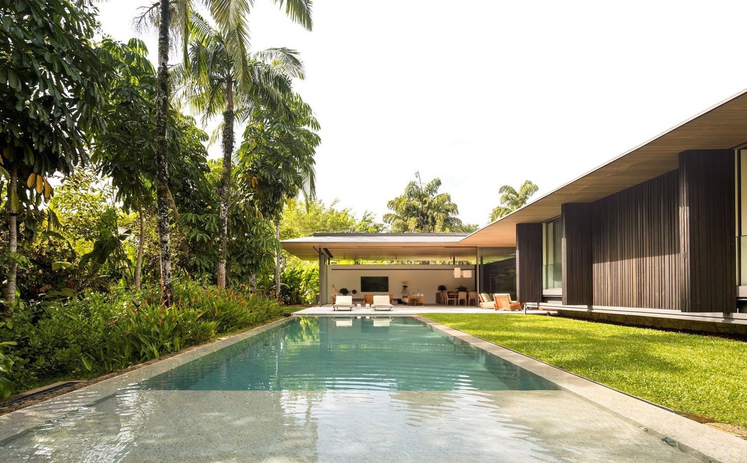 Exterior piscina junto a zona ajardinada y porche
