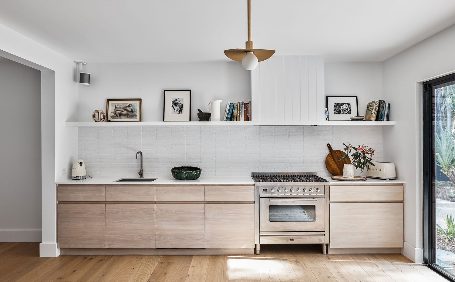 Cocina abierta con frentes de armario de madera, encimera blanca y balda superior blanca 