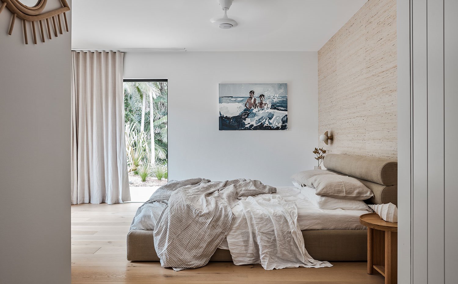 Dormitorio con ropa de cama y cortinas de tejido natural, suelo de madera, cabecero de forma ondulante