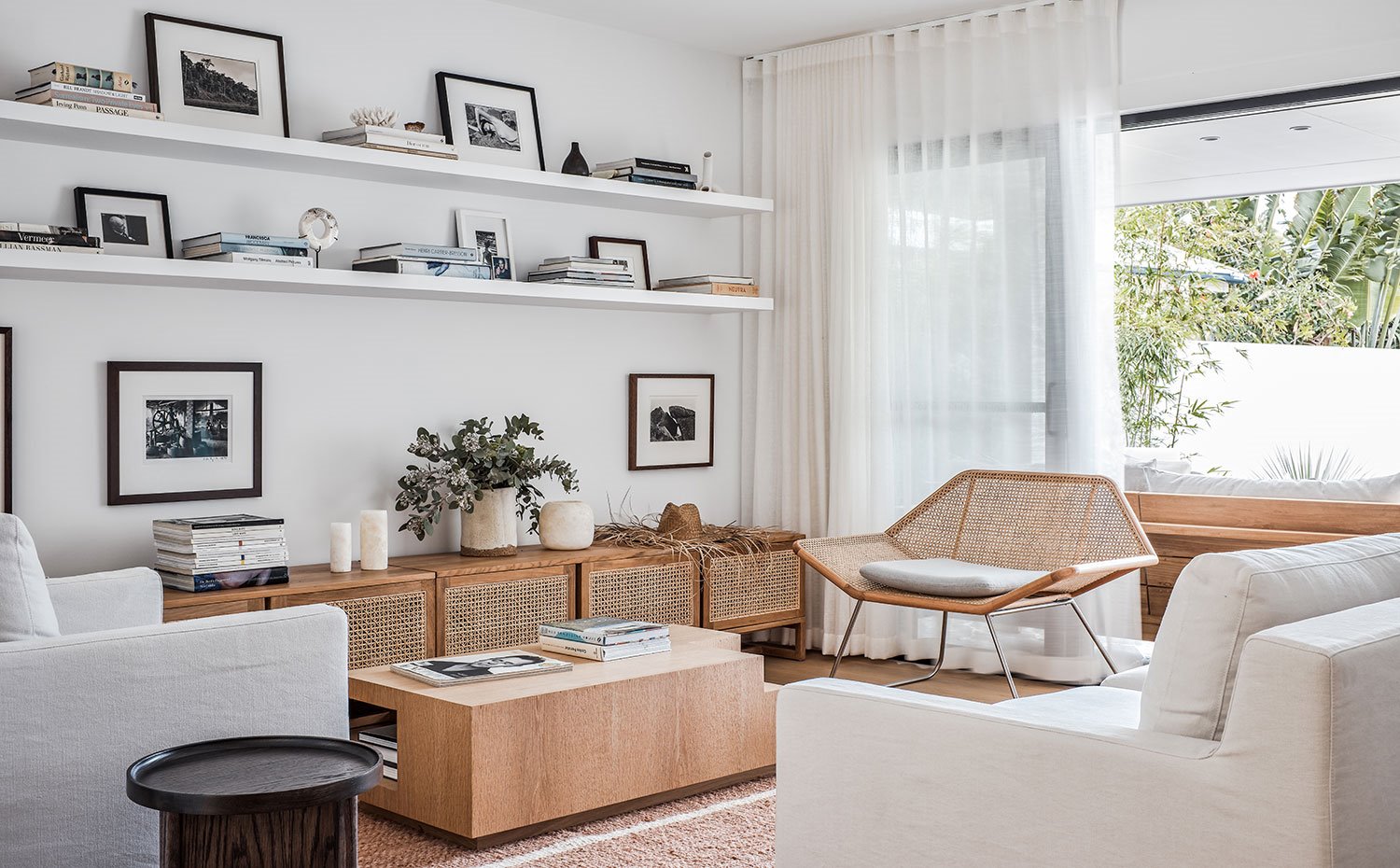 Salón con butaca de fibra trenzada, sofá y sillón gris claro, mesa y mueble bajo de madera y fibra