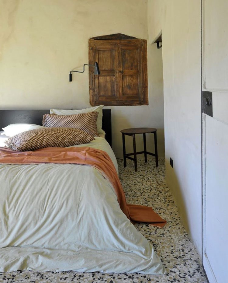 Detalle dormitorio con ventana de madera, suelo de gres, aplique cromado