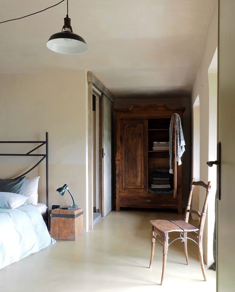 Dormitorio con cama con cabecero de hierro, mesilla, silla y armario de madera, cerramiento puerta corredera