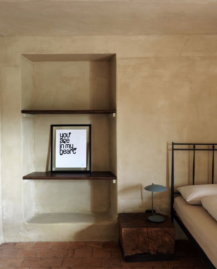 Dormitorio con hueco en pared con baldas a modo de estantería, mesilla de madera