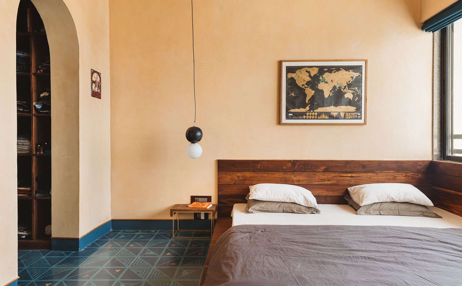 Dormitorio con cabecero de cama de madera, suelo con motivos azules y arco hacia vestidor 