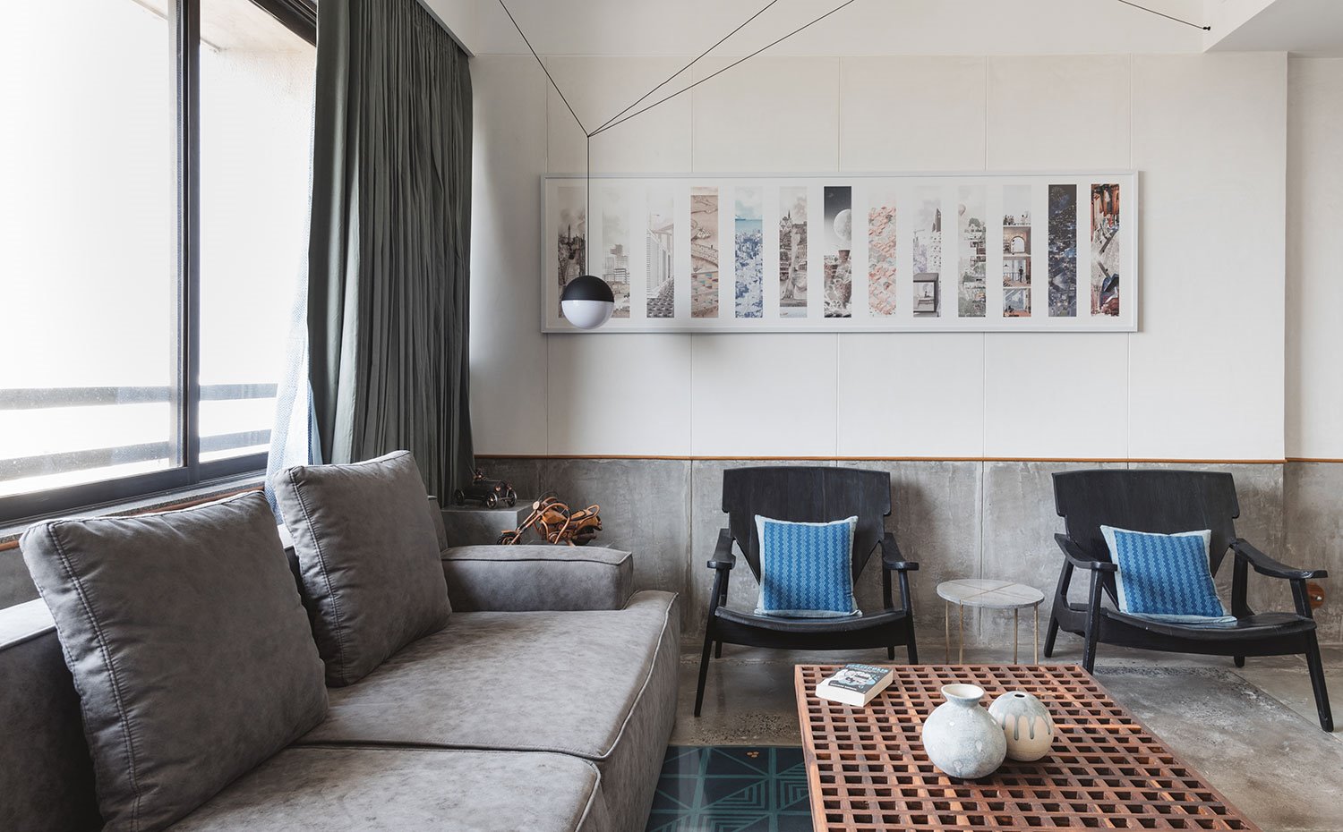 Salón con sofá gris, butacas negras y mesa de madera 