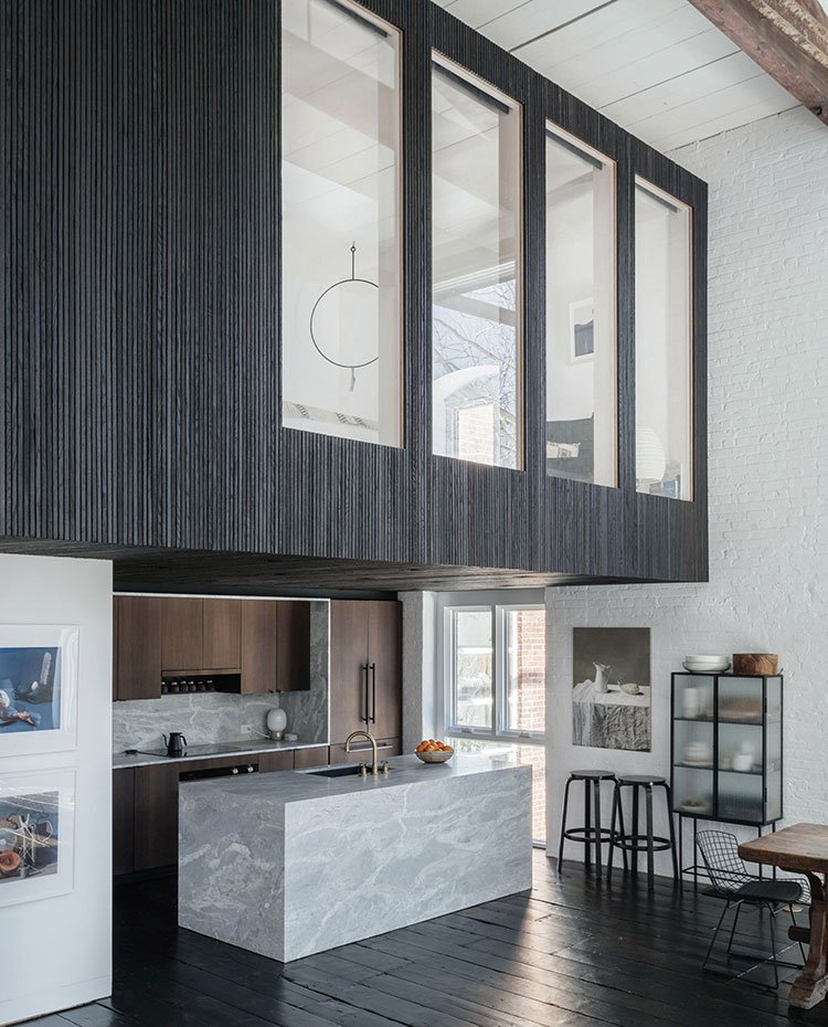 Cocina abierta con isla de piedra, cubículo nivel superior con aperturas verticales