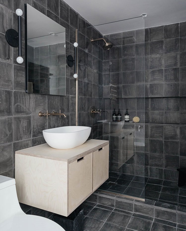 Cuarto de baño con revestimiento de gres en gris, mobiliario de madera y lavamanos porcelánico