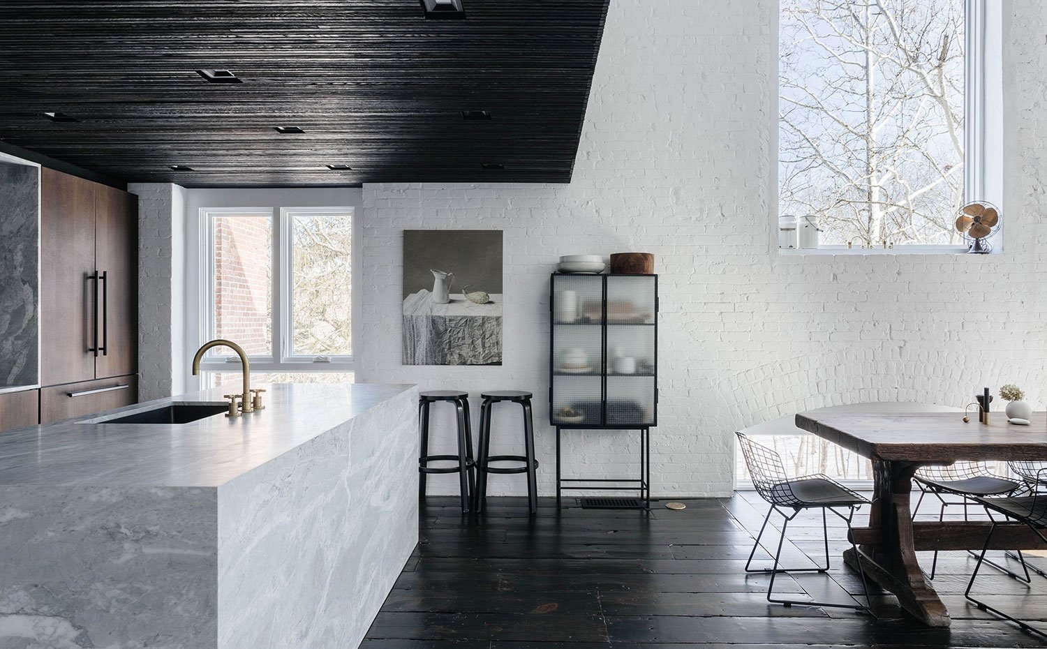 Cocina-abierta-al-comedor-con-isla-de-mármol-y-suelo-de-madera-envejecida