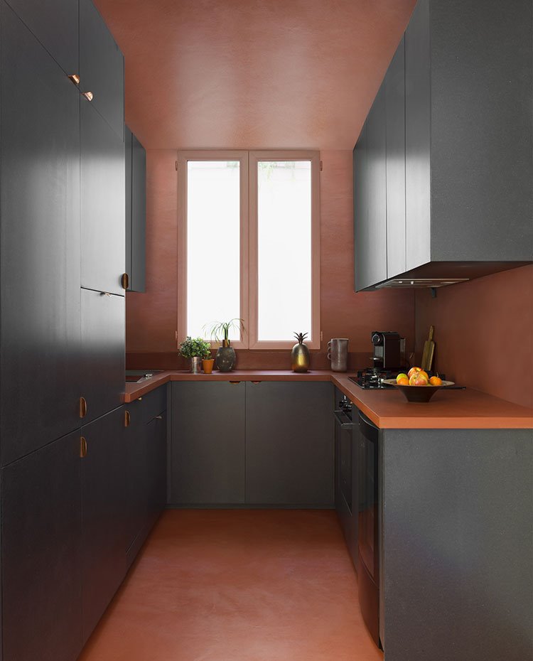 Cocina en forma de U con revestimiento y pavimento en tono teja, mobiliario en gris antracita, ventana frontal