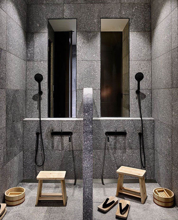 Duchas de obra con grifería negra, taburete y complementos en madera y bambú