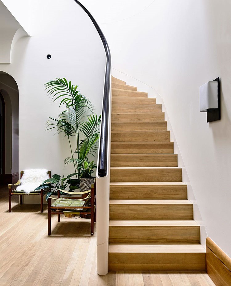 Escaleras circular con peldaños revestidos de madera y pasamanos circular en madera oscura, 