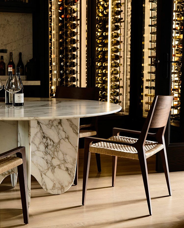 Mesa de centro circular de mármol, sillas de madera y mueble vitrina vinoteca