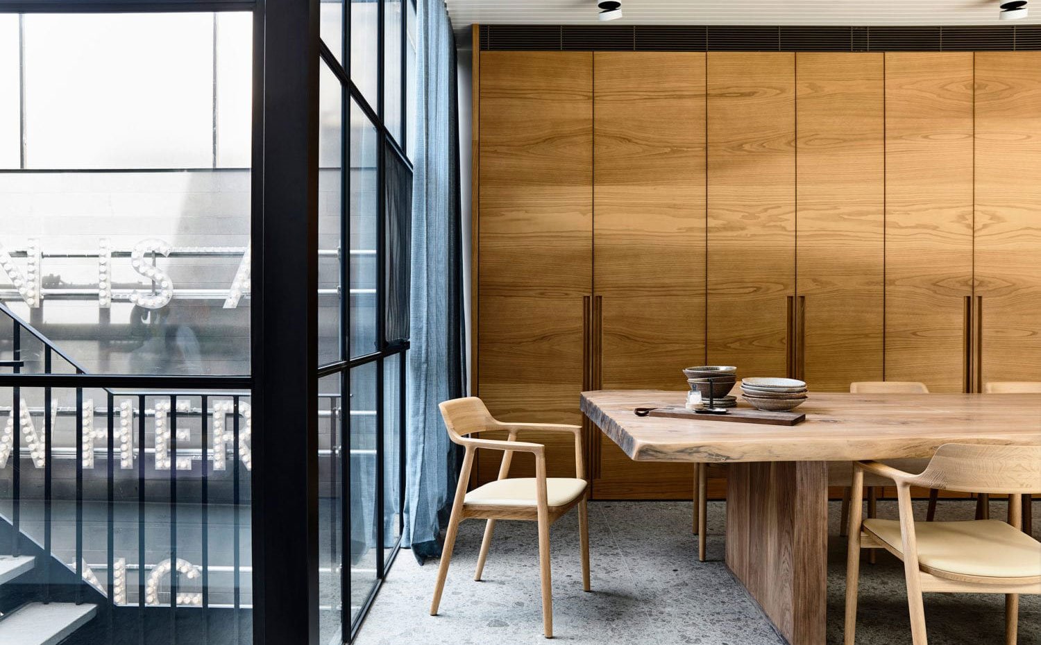 Zona de almacenaje junto a office, todo de madera, suelo porcelánico gris, patio exterior con cerramiento cristal