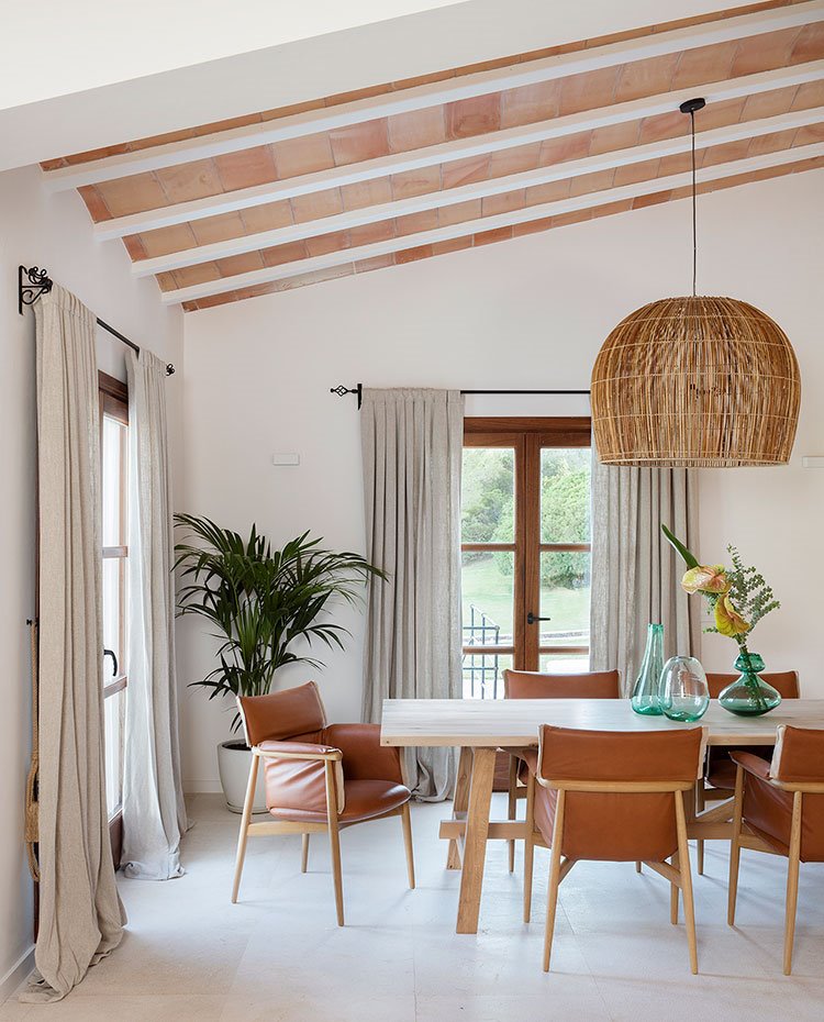 Comedor con sillas de piel y madera, techo con volta catalana, cortinas de lino
