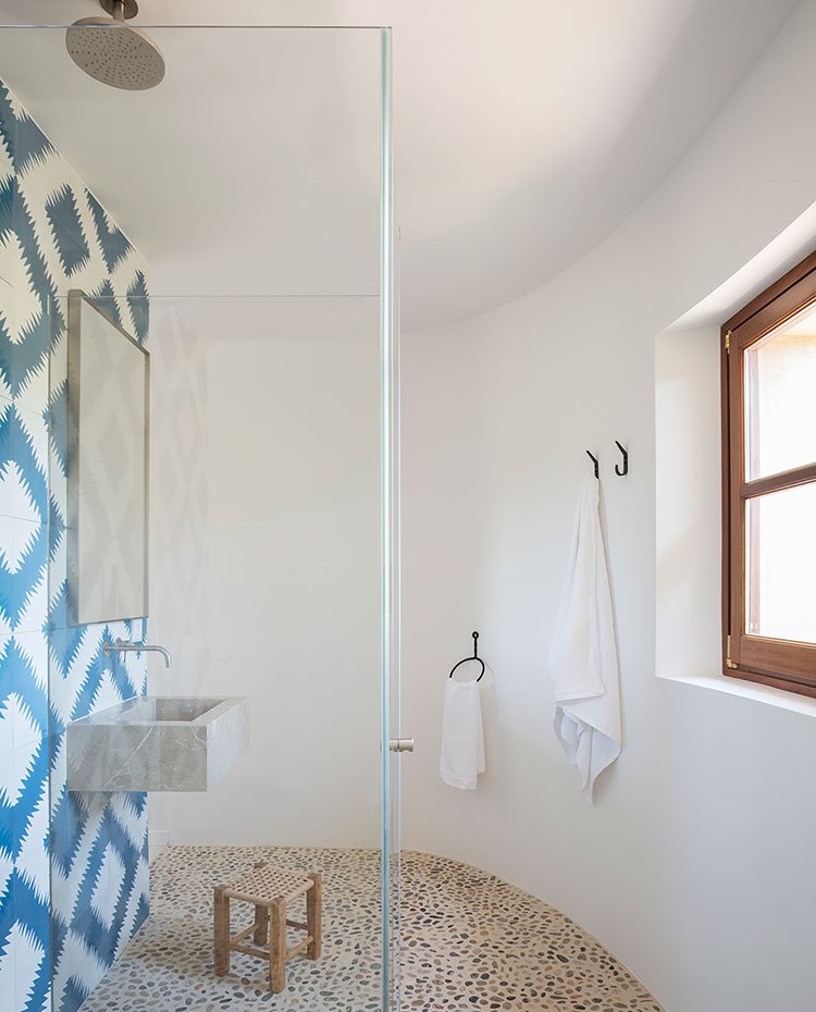 Cuarto de baño con suelo de canto rodado y revestimiento blanco y azul