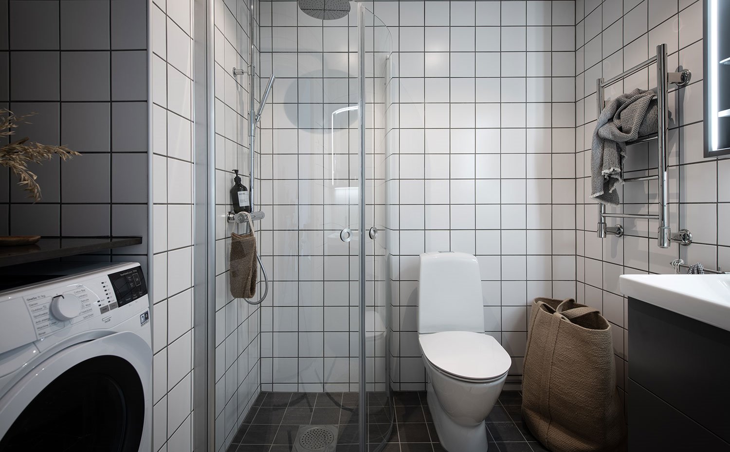 Cuarto de baño con baldosas blancas, ducha angular con mampara transparente