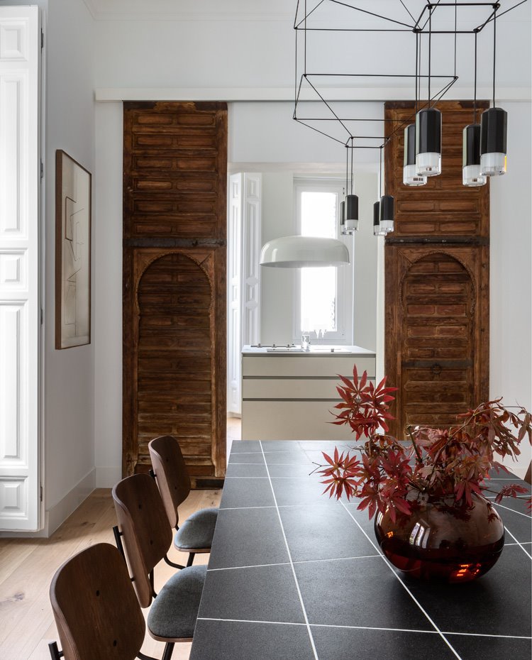 Comedor con gran mesa negra con rayas blancas, sillas de madera estilo vintage, puestar cerramientas en madera antigua