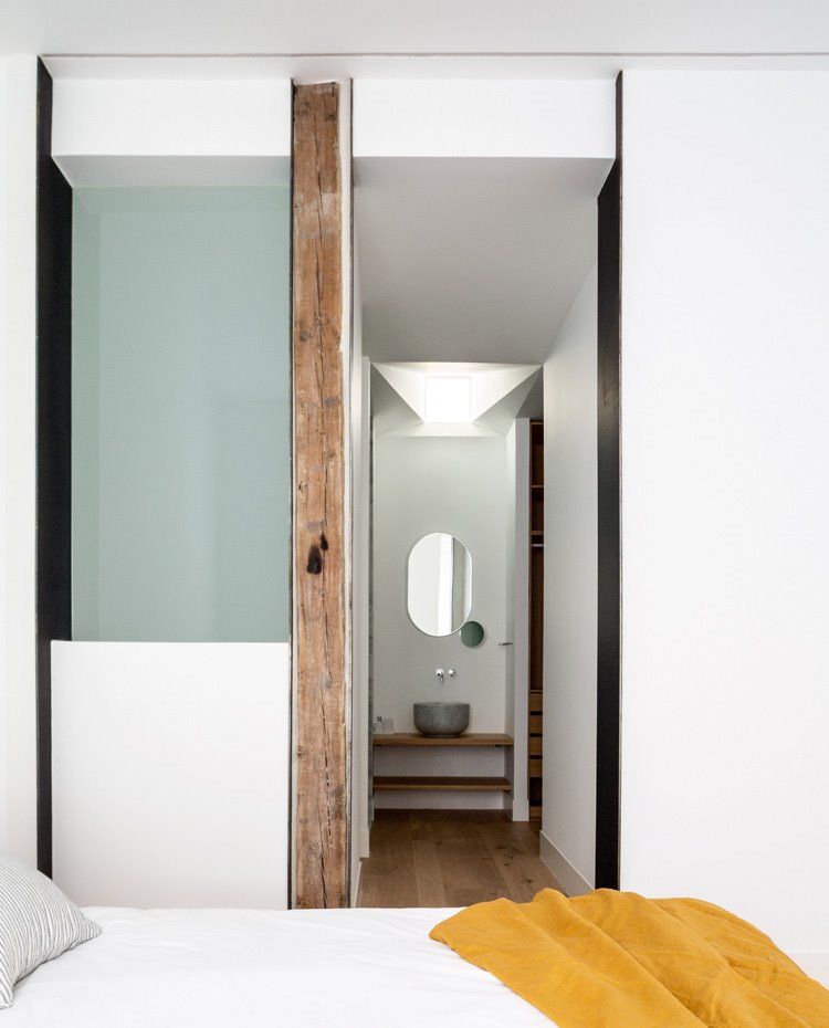 Tabique de madera en esquina de dormitorio con cerramiento de cristal translúcido