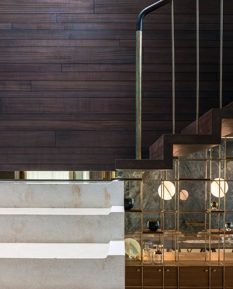 Detalle escaleras en mármol y madera con estantería de estructura dorada