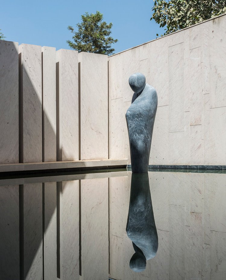 Escultura de piedra sobre base de agua envuelta de tabiquería de hormigón