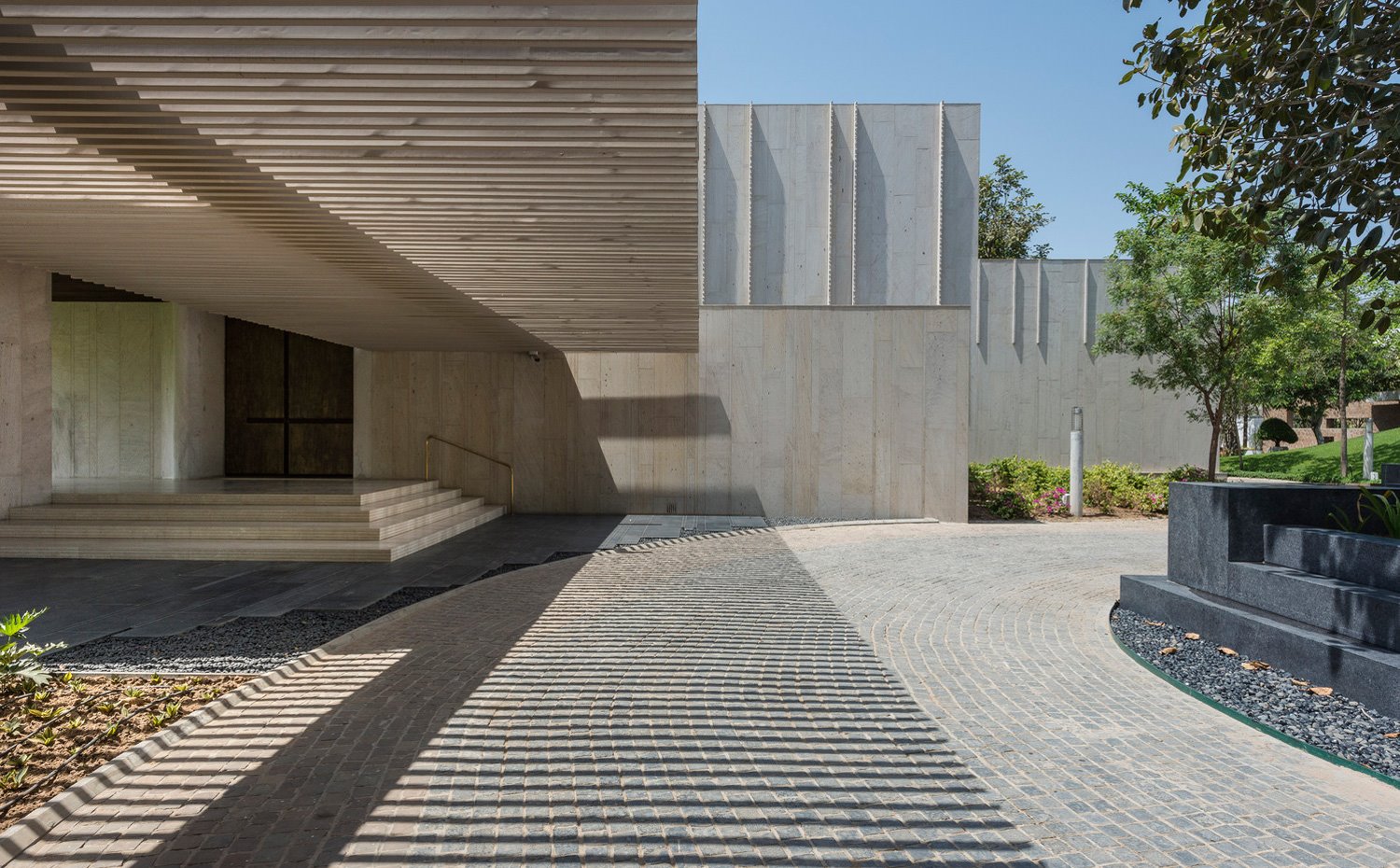 Zona de entrada con estructura de hormigón y porche en listones
